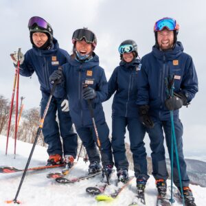 Far East Snowsports team instructors, including Tanya Hart, smiling together on the slopes of Niseko, Japan.