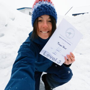 Tanya Hart smiling in the snow holding her APSI Level 3 ski instructor certificate in Niseko, Japan.