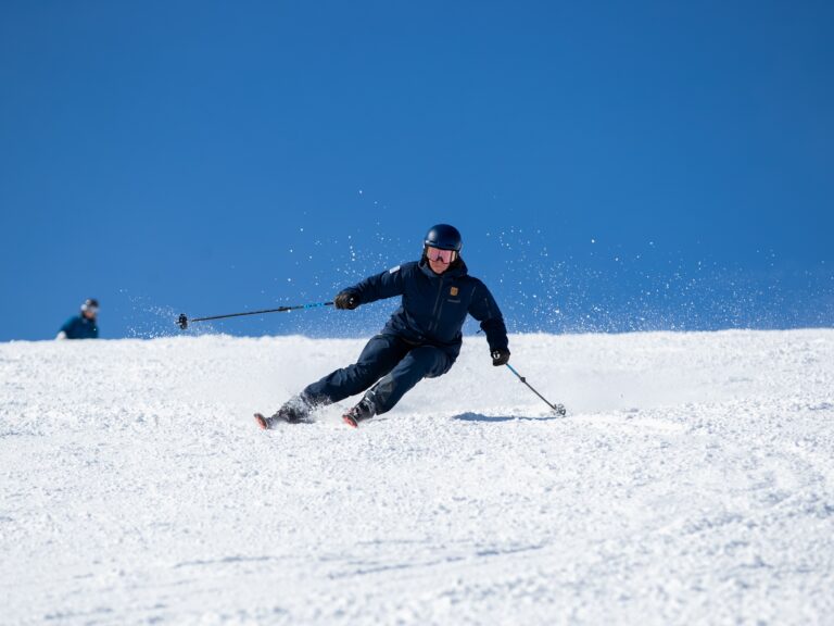 Tanya Hart carving turns on a sunny day in Niseko, Japan during a Women on Edge ski-treat.