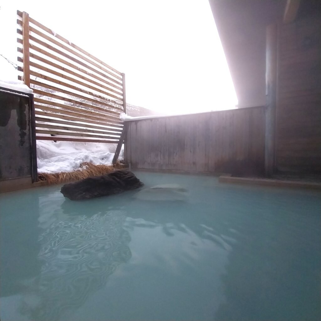 Traditional outdoor onsen surrounded by snow in Hokkaido, Japan.