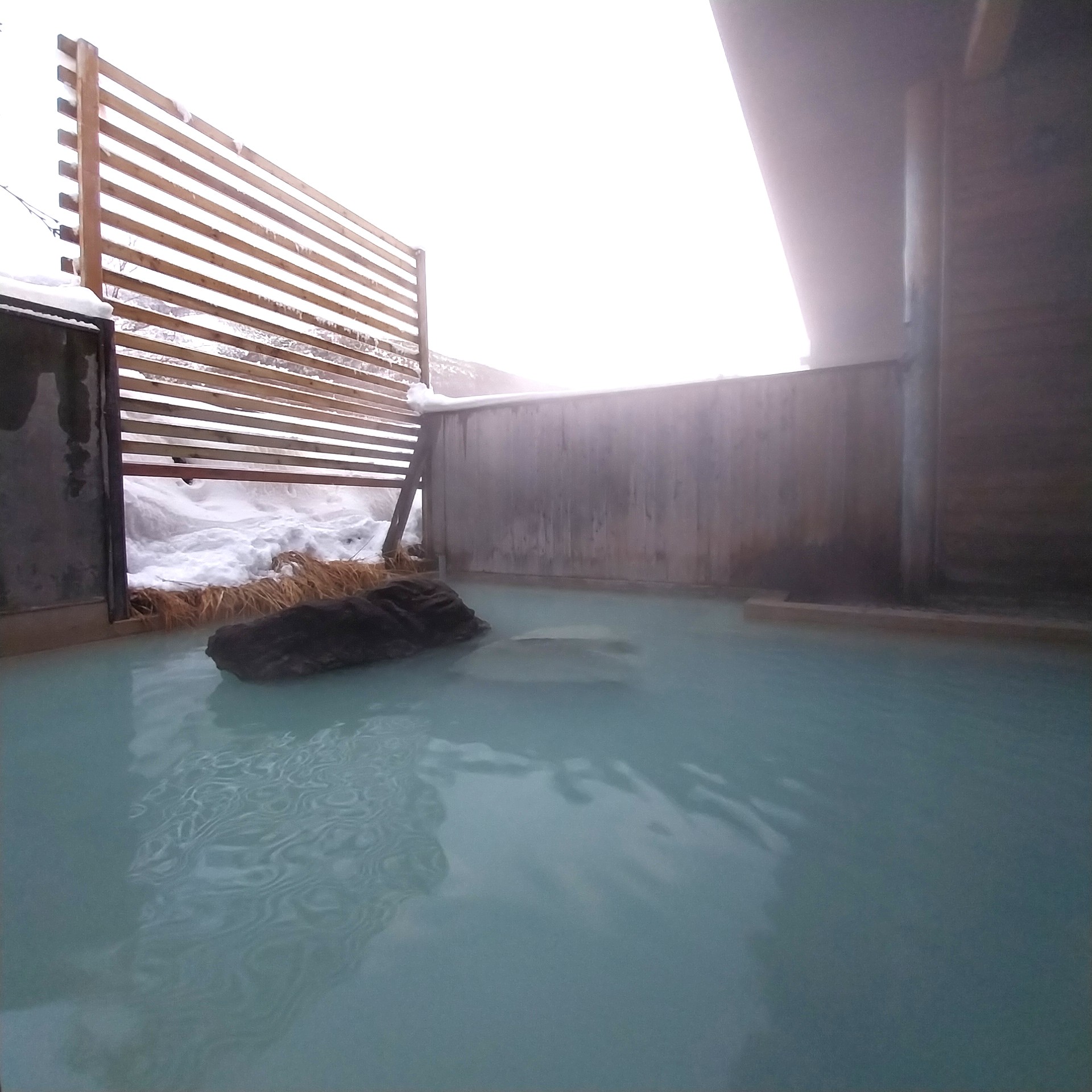 Traditional outdoor onsen surrounded by snow in Hokkaido, Japan.